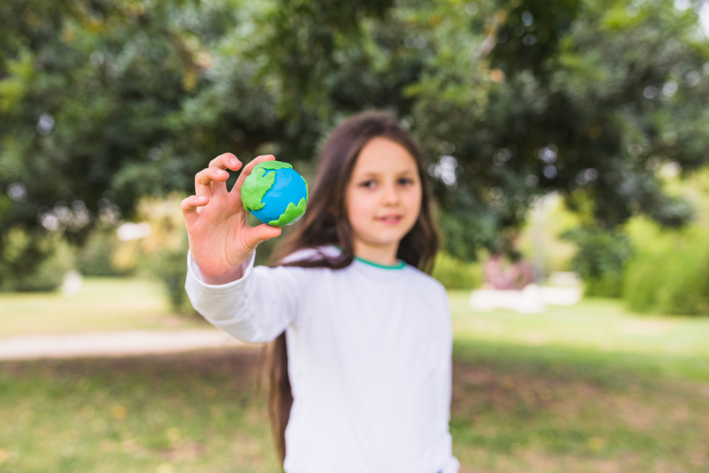 Criança segurando o globo terrestre na mão como forma de cuidado com o meio ambiente.