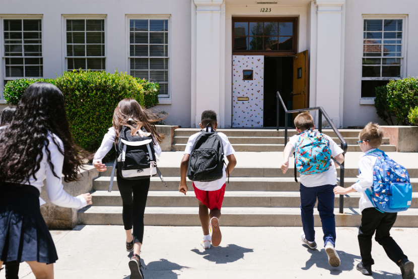 crianças entrando correndo felizes na escola.