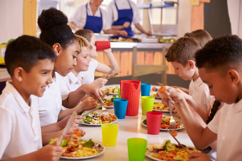 alunos  com pratos de comida se alimentando na escola