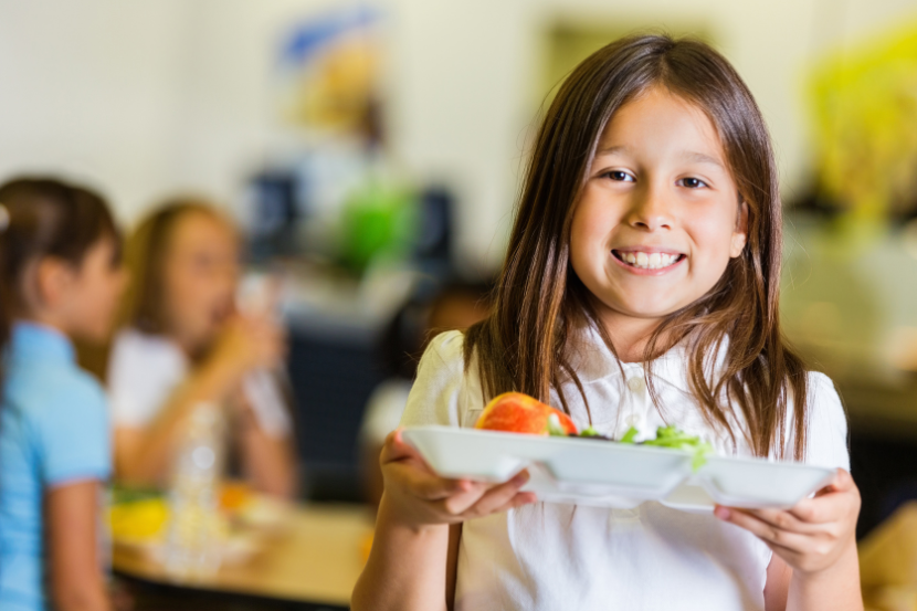 criança na escola com prato de comida na mão