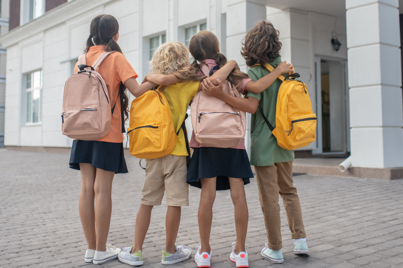 grupo de alunos abraçados na escola com mochila nas costas