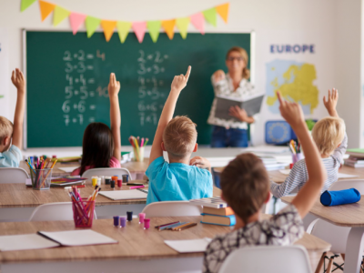 Professora e alunos em sala de aula usando notebooks com recursos de inteligência artificial.